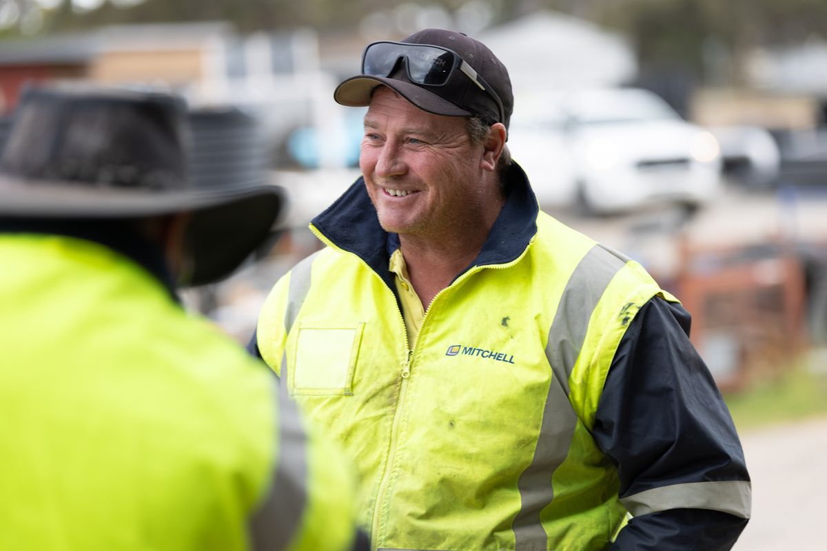 Smiling Mitchell crew member in a cap and hi-vis jacket on site